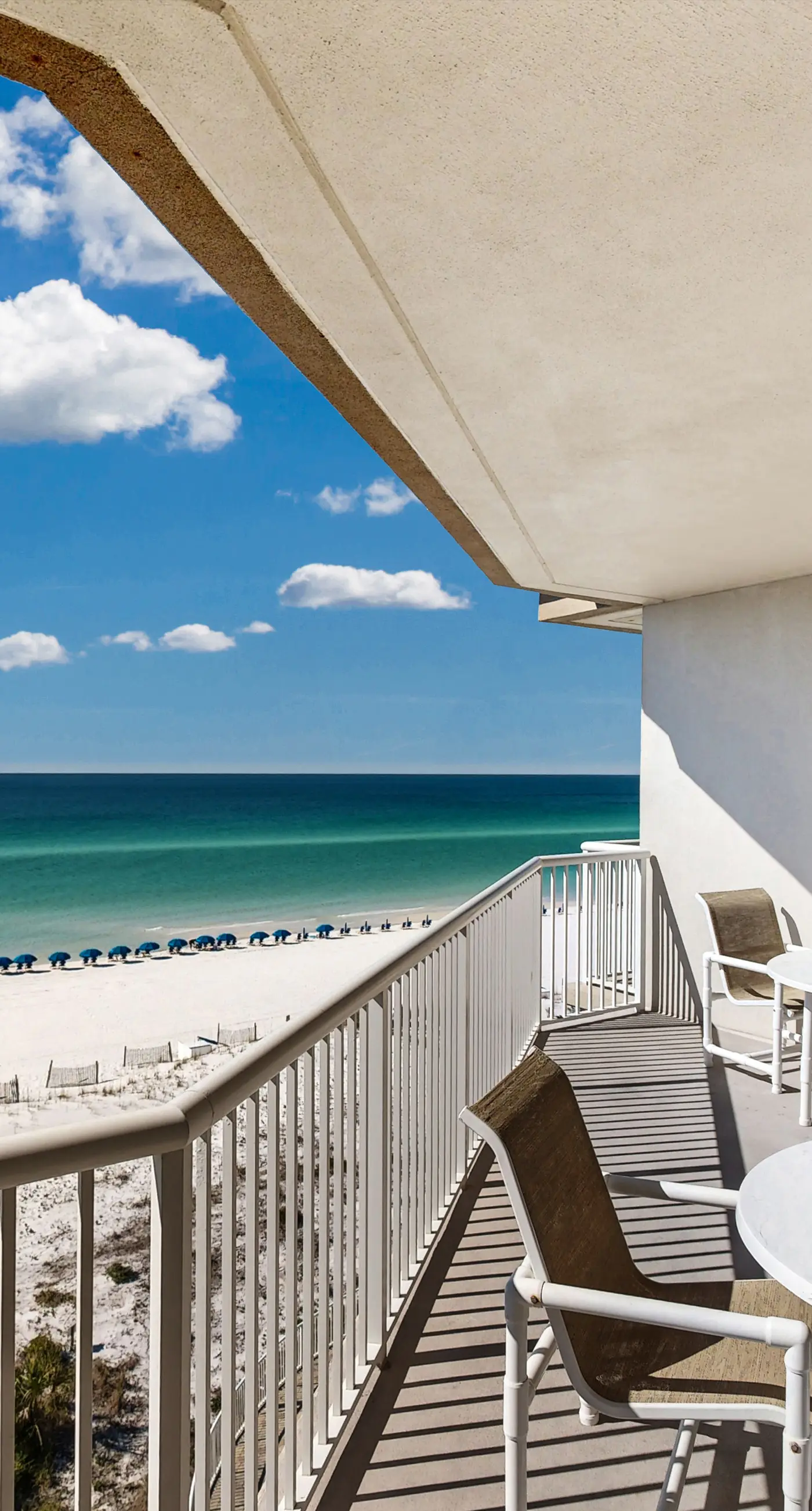 Beachfront condo with beach chairs, an umbrella, and a pool