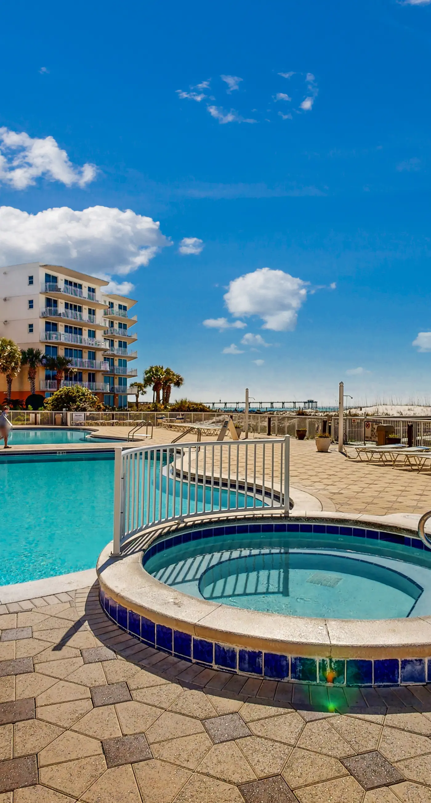 Beachfront condo with beach chairs, an umbrella, and a pool