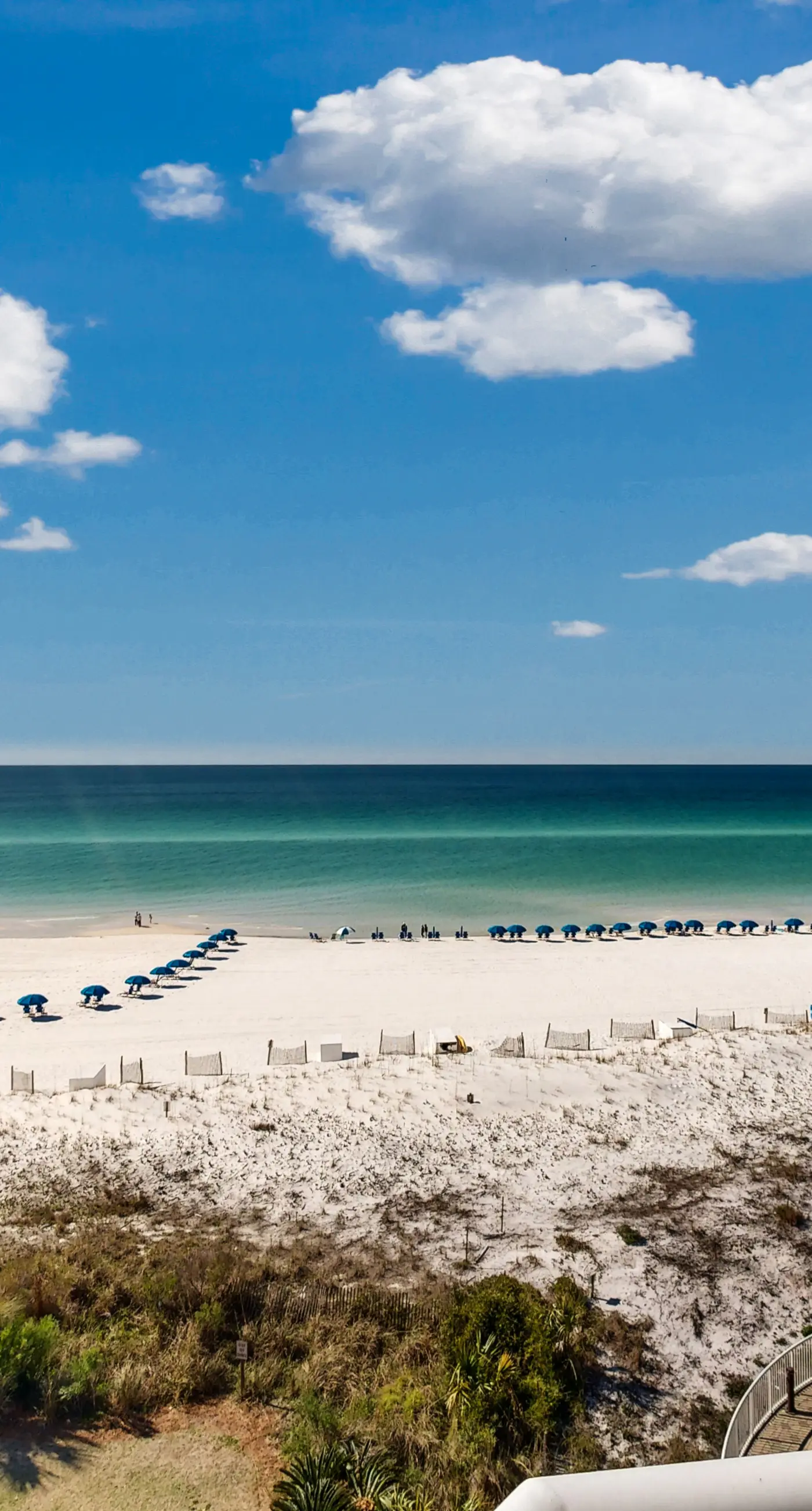 Beachfront condo with beach chairs, an umbrella, and a pool
