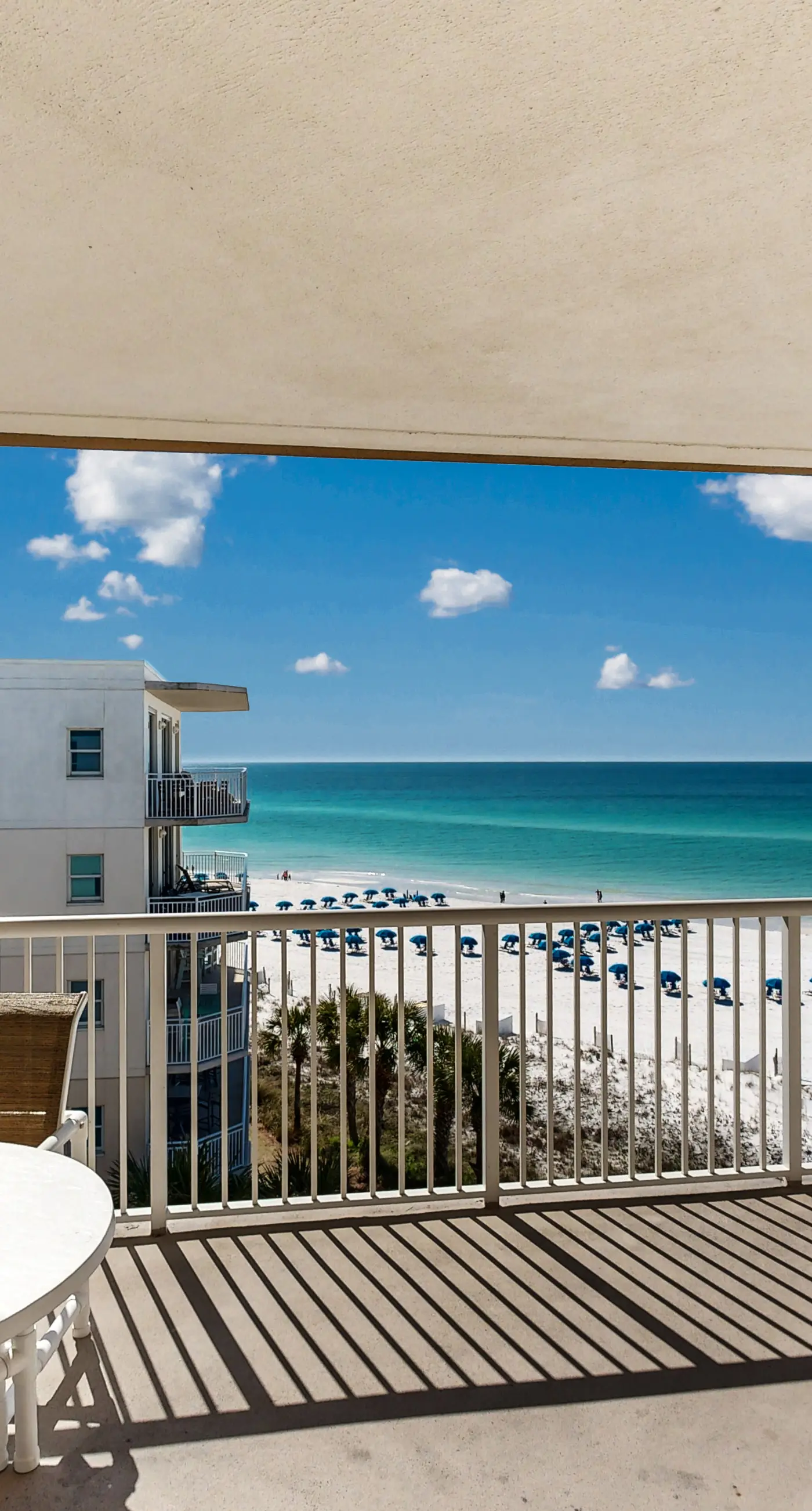 Beachfront condo with beach chairs, an umbrella, and a pool