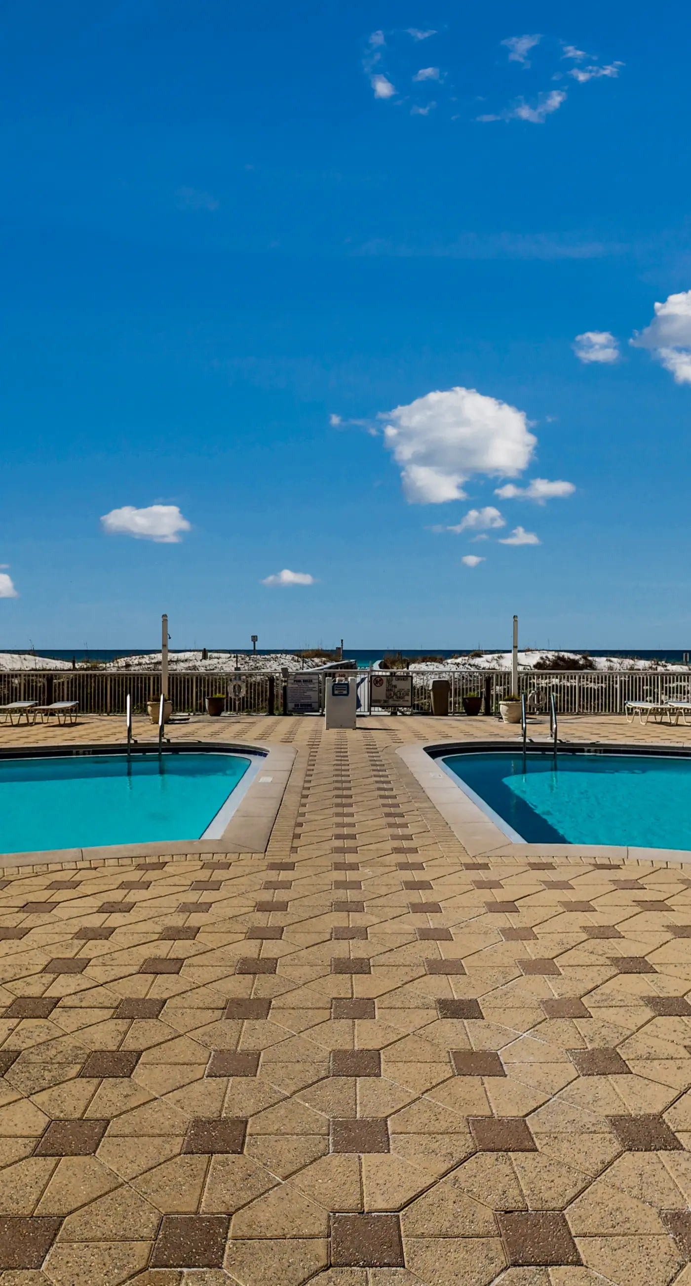 Beachfront condo with beach chairs, an umbrella, and a pool