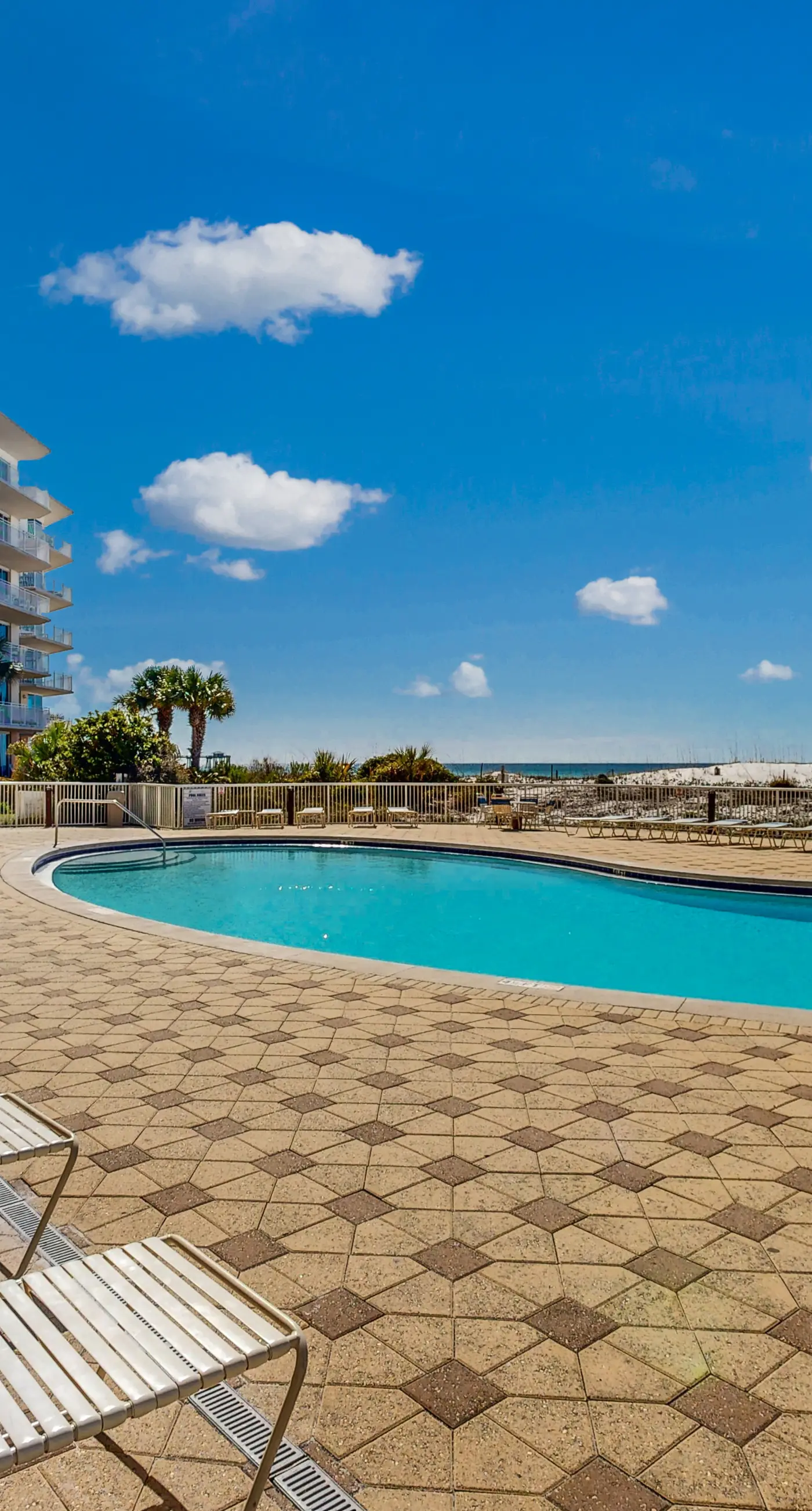 Beachfront condo with beach chairs, an umbrella, and a pool