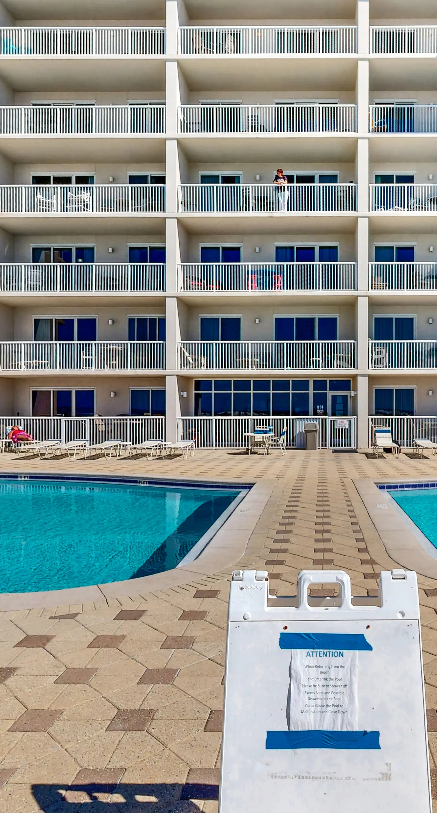 Beachfront condo with beach chairs, an umbrella, and a pool