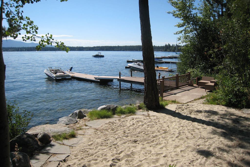 A classic lakefront cabin with floor-to-ceiling views of Payette Lake, private beach access, and a nostalgic McCall feel throughout. This cozy retreat features multiple sleeping spaces upstairs, a covered deck overlooking the lake, and a private dock with seating by the water. Wood-paneled interiors and vintage cabin charm create the quintessential McCall getaway experience.