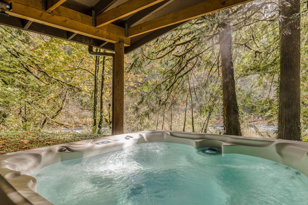 Spacious riverfront lodge with beach access, private hot tub & forest views