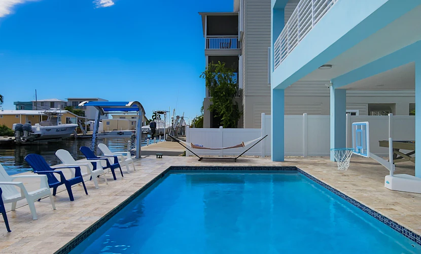 Sprawling waterfront home with pool, outdoor kitchen, game table, grill, & W/D