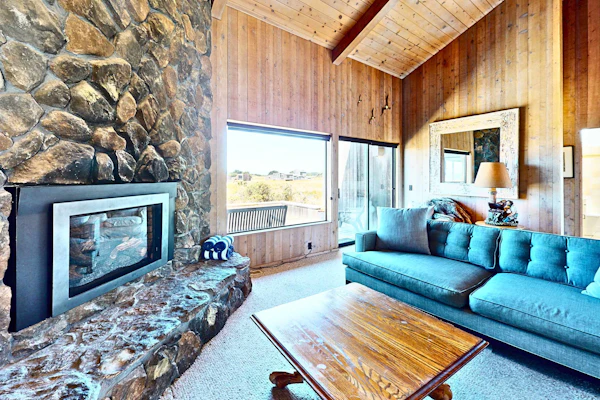 Unobstructed ocean views across a green coastal meadow -- the Pacific stretches to the horizon from your deck. Settle in by the floor-to-ceiling stone fireplace and watch the light change all day. Bring your pup -- dogs love the bluff trails here. Room for 4 in this 2-bedroom home. Sea Ranch community pools, tennis courts, and the Lodge are nearby. A private fenced courtyard with a gas grill makes sunset dinners easy. The ever-changing coastal light fills this home from morning fog to golden evening.
