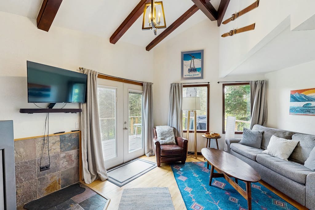 A modern cabin that proves contemporary lines and Girdwood’s deep woods don't have to fight. Tucked into a quiet, secluded pocket of trees a mile and a half from Alyeska Resort, this retreat trades the bustle of the village center for absolute mountain privacy. The architecture boasts towering ceilings, modern upscale furnishings, a custom spiral staircase climbing to a private loft bedroom, and a massive outdoor deck pointed at the peaks. Walk to Girdwood Brewing Company or Chair 5 Restaurant, and bring the dog along—they are completely welcome here. *4WD/traction tires strictly required in winter.* Standard Specs: Fully equipped kitchen, private mountain-view deck, flat-screen TV, high-speed WiFi, and keypad entry. Driveway parking for two vehicles. Dog-friendly. Sleeps 6.