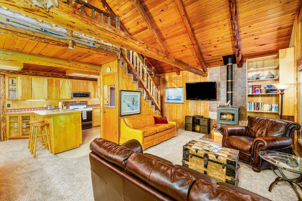 Log cabin living executed exactly the way it should be. Alpine Meadows Log Cabin sits a mile from Girdwood Park and minutes from the direct base of Alyeska Resort—offering a clean mountain escape that allows you to completely disconnect from the digital noise. The architecture features massive traditional log walls, a forest closing in on all sides, an expansive wrap-around deck built for summer sunbathing or stargazing, and large picture windows that flood the rustic space with natural light. Stowe the central wood stove on cold winter nights, cook real meals in the full kitchen, and use the private washer and dryer to keep gear dry. Standard Specs: Fully equipped kitchen with complete cookware, traditional wood stove, expansive private deck, private in-unit washer/dryer, flat-screen TV, high-speed WiFi, and keypad entry. Driveway parking for two vehicles. Sleeps 6.