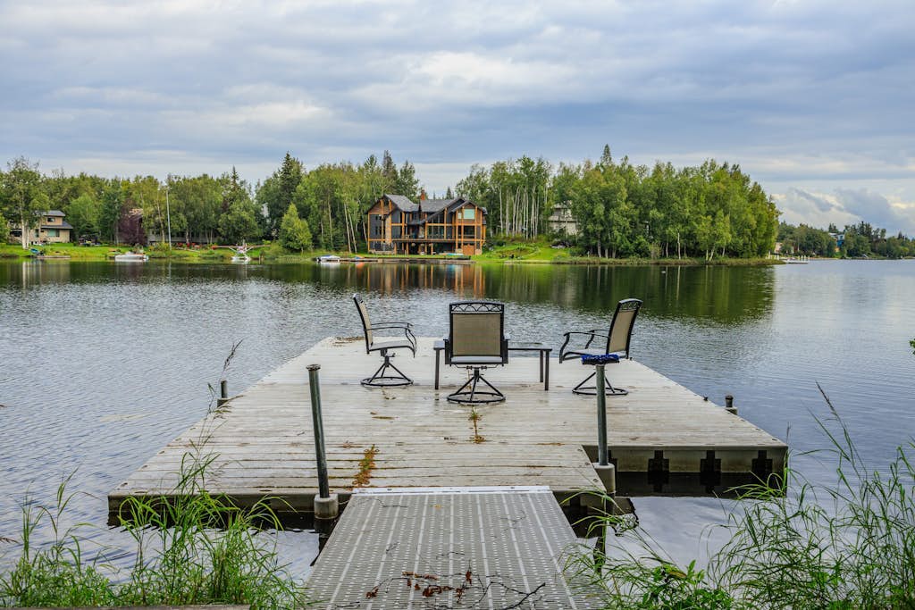 The kind of high-end Anchorage estate that anchors an entire multi-generation vacation or corporate campaign. Perched on a private lot on the shores of Sand Lake, this massive 4,500-square-foot home sits just minutes from the airport and four miles from Kincaid Park, while providing a clean highway shot down to the Girdwood valley. The property features a private boat dock on the water, provided stand-up paddleboards (SUPs), and a waterfront hammock, while turning into a cross-country ski loop in the winter. Inside, discovery awaits with two gas fireplaces, an exercise room, an air hockey table, a master jetted soaking tub, and a limited-mobility accessible ground-floor suite with its own independent kitchen and bath. Standard Specs: Two full kitchens, two gas fireplaces, private boat dock, stand-up paddleboards, indoor exercise room, air hockey table, master jetted tub, private laundry, flat-screen TVs, high-speed WiFi, and keypad entry. Parking for three vehicles. Sleeps 10.