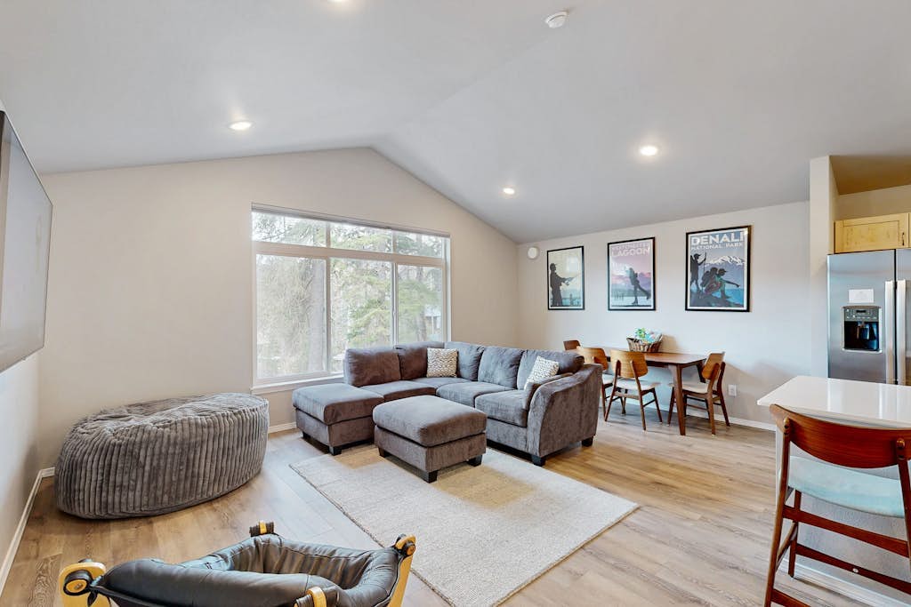 Modern radiant floor heating is the subtle operational detail that turns a winter ski trip into a true luxury upgrade—and Girdwood Vibes Unit B features it throughout the entire open-concept floor plan. Located within easy walking distance of Alyeska Resort and the Virgin Creek Trailhead, this suite handles family logistics effortlessly. The interior features an oversized living room sofa, a large custom bean bag, a massive Smart TV, and a full kitchen with stainless steel appliances. The dedicated kid's room comes fully stocked with toys, books, and games to handle the entertainment heavy lifting, while the back deck opens out to a shared grilling area framed by clean mountain peaks. Standard Specs: Full kitchen with stainless steel appliances, radiant floor heating, shared deck with gas grill, private washer/dryer, flat-screen Smart TV, child's toys, games, books, Pack-N-Play, high-speed WiFi, and keypad entry. Parking for two vehicles. No A/C. Sleeps 6.