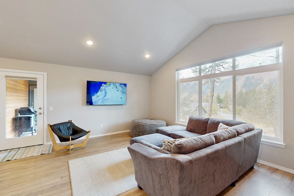 Modern radiant floor heating is the subtle operational detail that turns a winter ski trip into a true luxury upgrade—and Girdwood Vibes Unit B features it throughout the entire open-concept floor plan. Located within easy walking distance of Alyeska Resort and the Virgin Creek Trailhead, this suite handles family logistics effortlessly. The interior features an oversized living room sofa, a large custom bean bag, a massive Smart TV, and a full kitchen with stainless steel appliances. The dedicated kid's room comes fully stocked with toys, books, and games to handle the entertainment heavy lifting, while the back deck opens out to a shared grilling area framed by clean mountain peaks. Standard Specs: Full kitchen with stainless steel appliances, radiant floor heating, shared deck with gas grill, private washer/dryer, flat-screen Smart TV, child's toys, games, books, Pack-N-Play, high-speed WiFi, and keypad entry. Parking for two vehicles. No A/C. Sleeps 6.