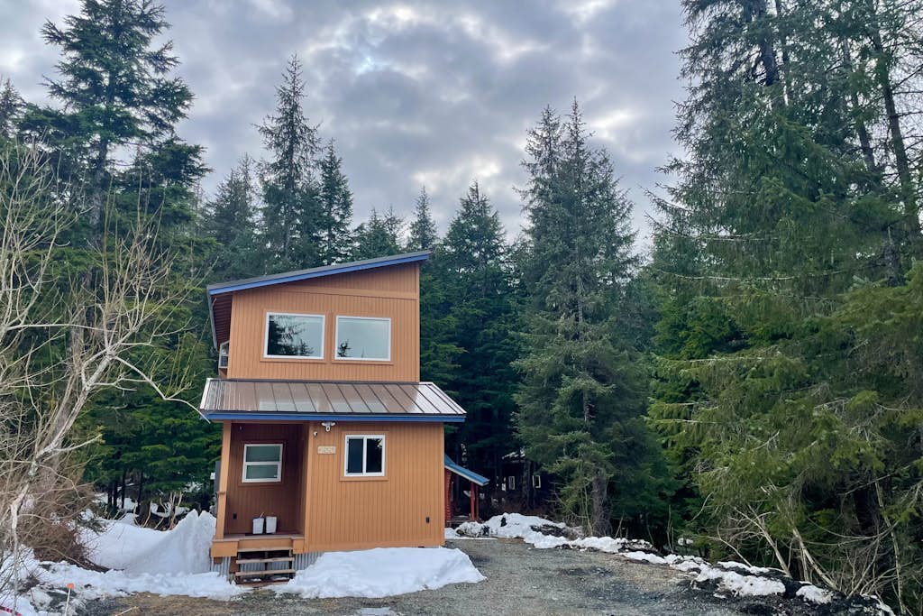 The exact kind of bright, open-concept one-bedroom home you would actually choose to live in full-time. Large upper-level architectural windows pull the mountain and valley views right into the main living room, while a private balcony pushes you straight out into the fresh Girdwood air. The intelligent multi-level layout features a full eat-in dining bar, an updated kitchen, and a lower-level master bedroom with an oversized walk-in closet and private laundry. A dedicated downstairs bonus room cleanly handles yoga practice, remote work, or quiet gear storage. Located a brief drive to Alyeska Resort and steps from local trail loops and breweries. Standard Specs: Full kitchen with dishwasher, private balcony, walk-in closet, full-size utility washer/dryer, dedicated yoga/storage room, board games, flat-screen TV with Netflix streaming, high-speed WiFi, and keypad entry. Driveway parking for two vehicles. Sleeps 5.