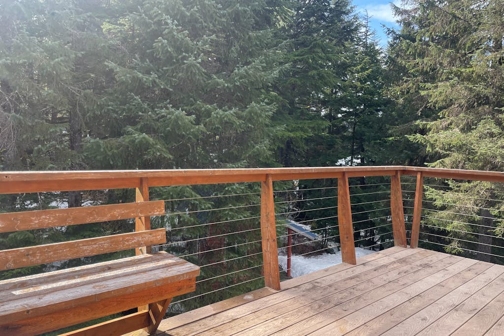 The exact kind of bright, open-concept one-bedroom home you would actually choose to live in full-time. Large upper-level architectural windows pull the mountain and valley views right into the main living room, while a private balcony pushes you straight out into the fresh Girdwood air. The intelligent multi-level layout features a full eat-in dining bar, an updated kitchen, and a lower-level master bedroom with an oversized walk-in closet and private laundry. A dedicated downstairs bonus room cleanly handles yoga practice, remote work, or quiet gear storage. Located a brief drive to Alyeska Resort and steps from local trail loops and breweries. Standard Specs: Full kitchen with dishwasher, private balcony, walk-in closet, full-size utility washer/dryer, dedicated yoga/storage room, board games, flat-screen TV with Netflix streaming, high-speed WiFi, and keypad entry. Driveway parking for two vehicles. Sleeps 5.