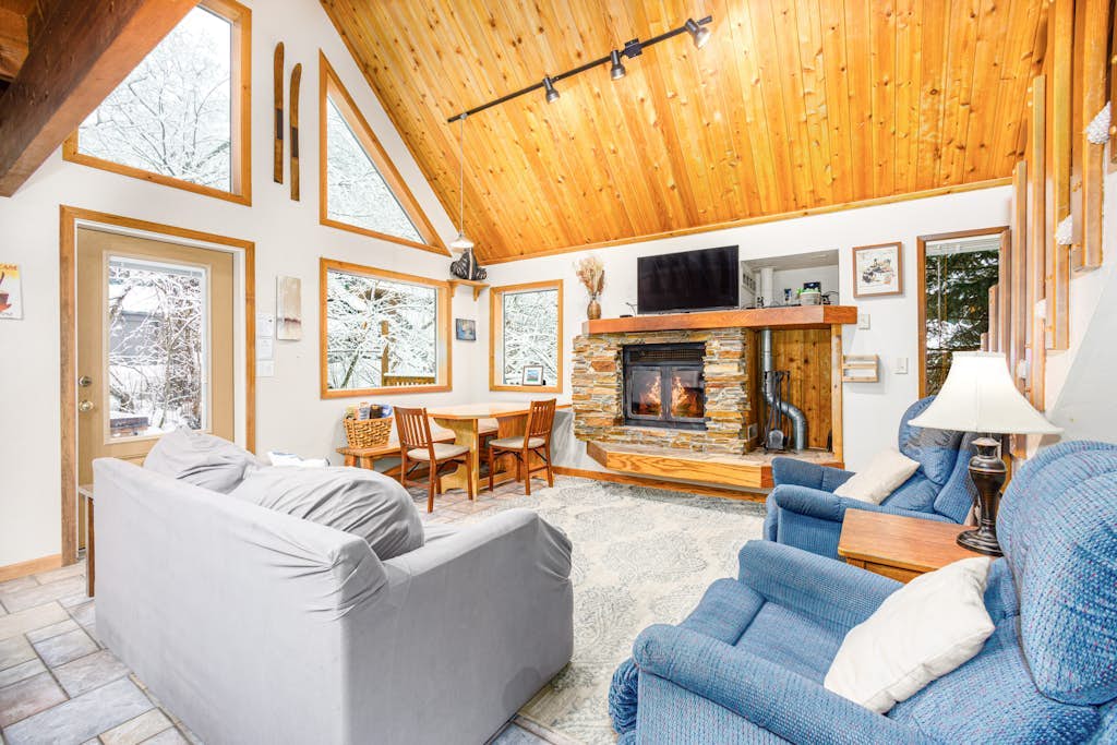 A classic mountain chalet that delivers authentic cabin warmth, positioned just an easy walk from the main chairlifts at Alyeska Resort. Built with large architectural windows that draw the Chugach peaks inside, this multi-level layout is the perfect staging ground for deep-powder winters or summer trail campaigns up Crow Pass and Winner Creek. The interior centers around a traditional wood-burning fireplace, a fully equipped kitchen built for hosting hearty post-trail meals, and a flexible loft space that cleanly handles extra guests. Dogs are welcome to join the adventure, and the private balcony offers a quiet place for morning coffee in the forest. *Please note: The footpath to the entrance involves authentic wooden walkways and uneven stairs.* Standard Specs: Fully equipped kitchen, wood-burning fireplace, smart streaming TV, high-speed WiFi, and keypad entry. Dedicated parking for two vehicles. No A/C. Dog-friendly. Sleeps 6.