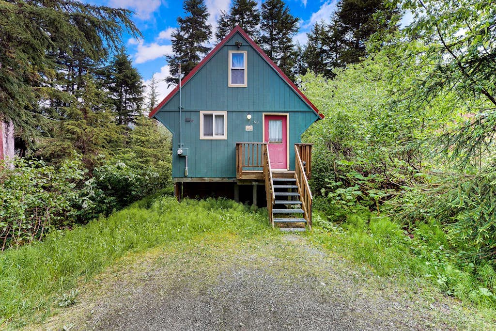 Christina Cabin is small on purpose. Tucked quietly into the forest under two miles from Alyeska Resort, this quaint alpine A-frame is an intentional, artsy retreat where the noise of the rest of the world completely disappears. The hand-styled interior features custom personal touches and high-quality furnishings, while the back patio holds a brand-new private hot tub enclosed by a custom wood privacy fence. Walk straight out your door to access local hiking loops, or take a quick drive to the village dining spots and aerial tramway. A clean, romantic space built for purists. Standard Specs: Well-equipped kitchen, private outdoor hot tub with privacy fencing, flat-screen TV, high-speed WiFi, and keypad entry. Driveway parking for two vehicles. Strict compliance with local quiet hours (10 PM–8 AM) and non-smoking premises. Sleeps 2.