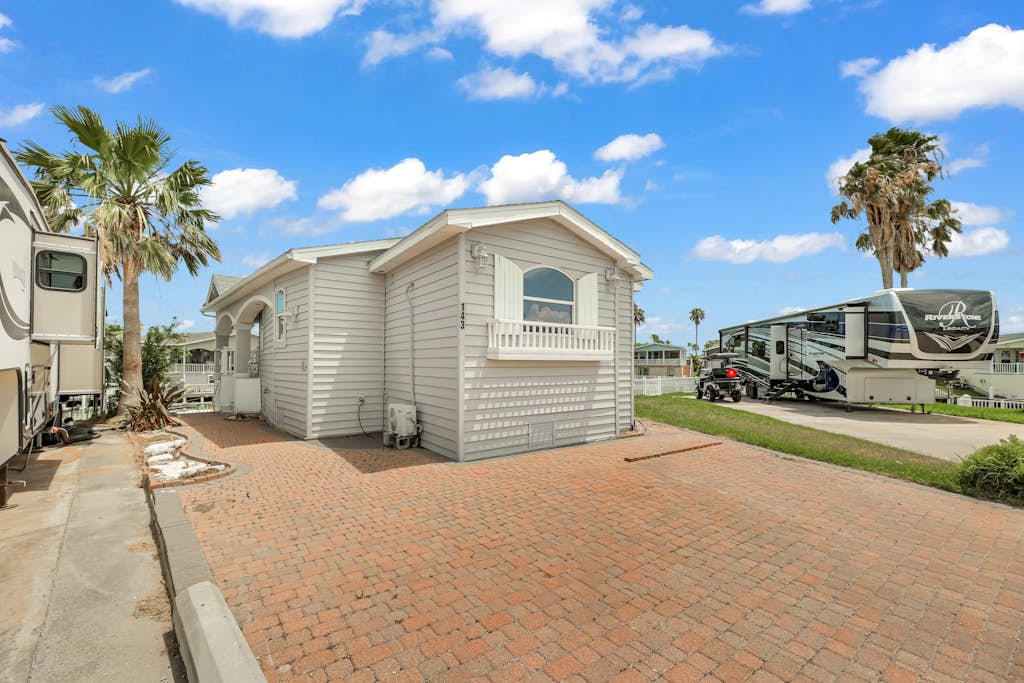 Welcome to Waterfront Oasis, a bright single-level cottage on a quiet canal in the gated Long Island Village resort. Sip coffee on the covered patio while the water glistens just beyond the rail, cast a line from the dock, then settle into one of two restful queen bedrooms. Step out to community pools, an indoor hot tub, par-3 golf, tennis, and pickleball, with South Padre Island beaches a short drive over the causeway. Your Texas Gulf Coast escape starts here.