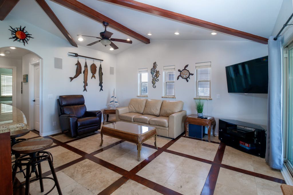 Welcome to Copper Bottom Cottage, a four-bedroom waterfront retreat in the channels of gated Long Island Village. Gather on the spacious covered deck above the canal, fish from the water's edge, and spread out across two levels with room for eight. The lower unit has its own entrance, and every bedroom has a streaming TV. Your stay includes the community's indoor and outdoor pools, hot tubs, par-3 golf, tennis, and marina, with South Padre Island beaches about ten minutes over the causeway.