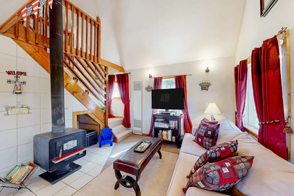 A-frame home lined by trees with wood stove, balcony, children's items, & W/D